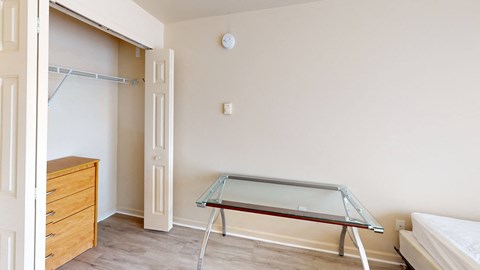 A glass table with metal legs sits in a room with a white wall and a door.